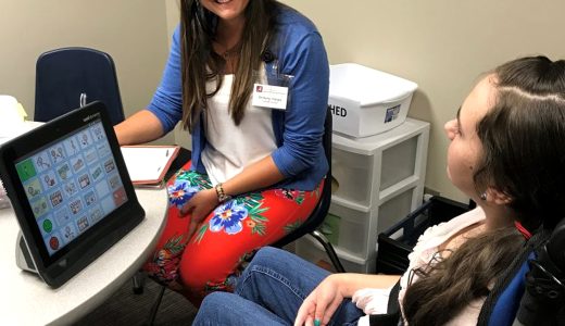Graduate clinician assisting a client who uses an AAC